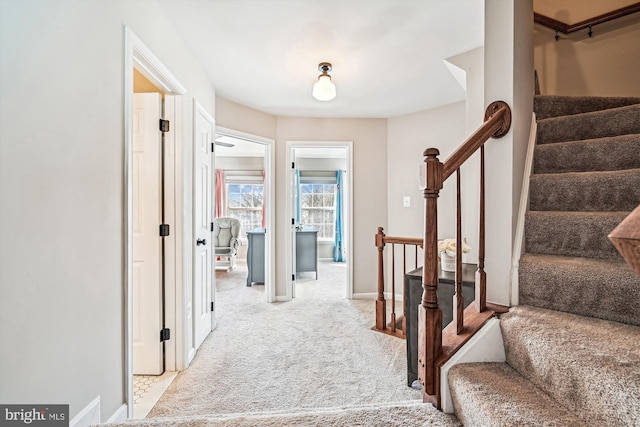 foyer with stairs, light colored carpet, and baseboards