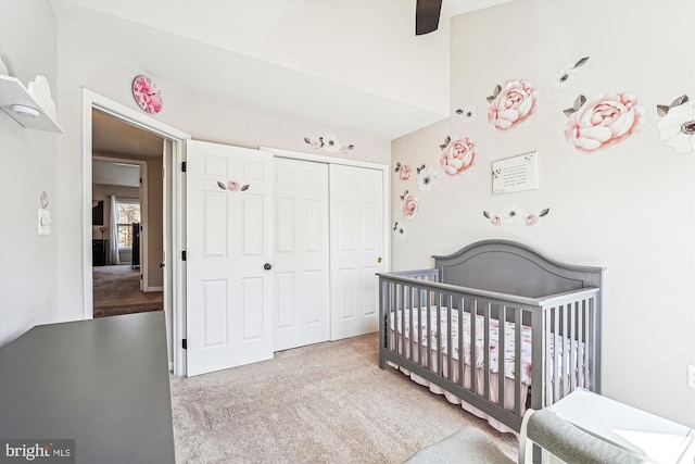 carpeted bedroom featuring a nursery area, a closet, and ceiling fan