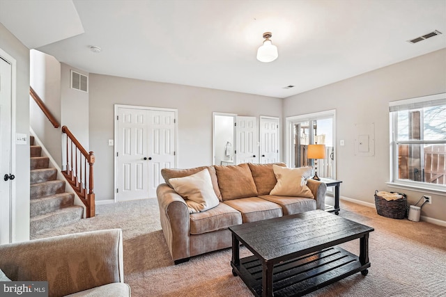 living area featuring stairway, light colored carpet, and visible vents