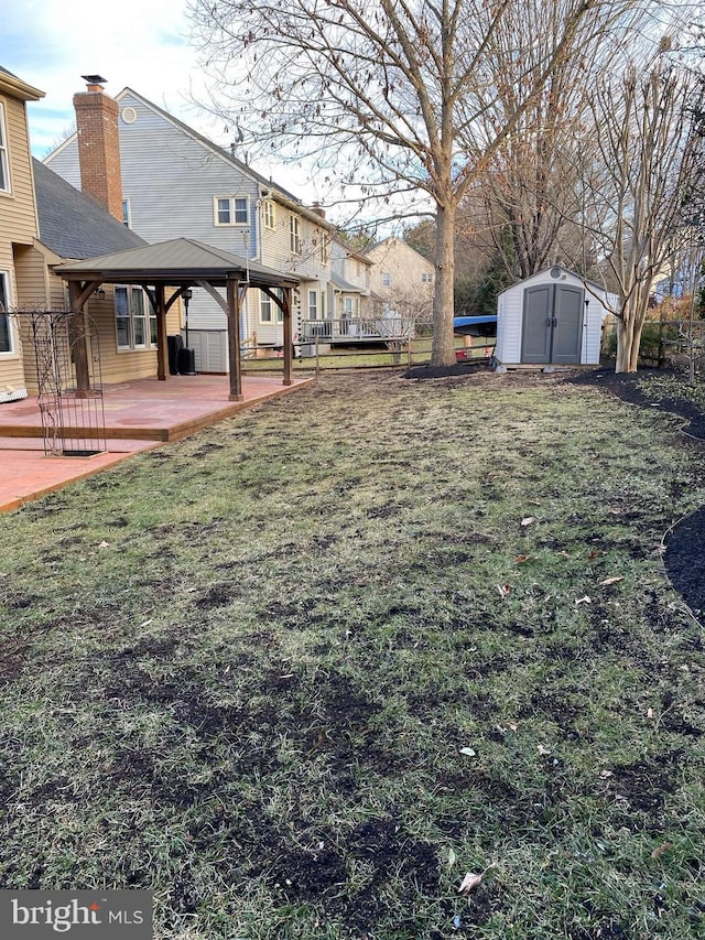 view of yard featuring a storage shed, a gazebo, fence, a deck, and an outdoor structure