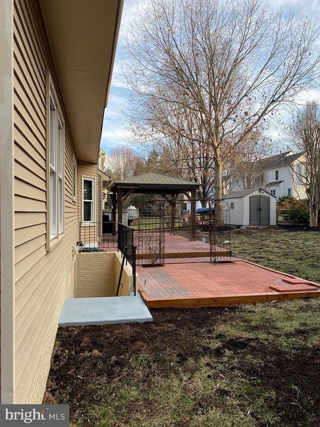 wooden deck featuring a storage shed, a gazebo, a yard, and an outbuilding