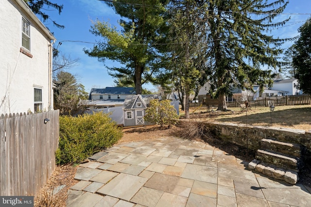 view of patio with an outbuilding, a storage shed, and fence