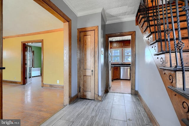 corridor with light wood finished floors, stairway, ornamental molding, a textured ceiling, and baseboards