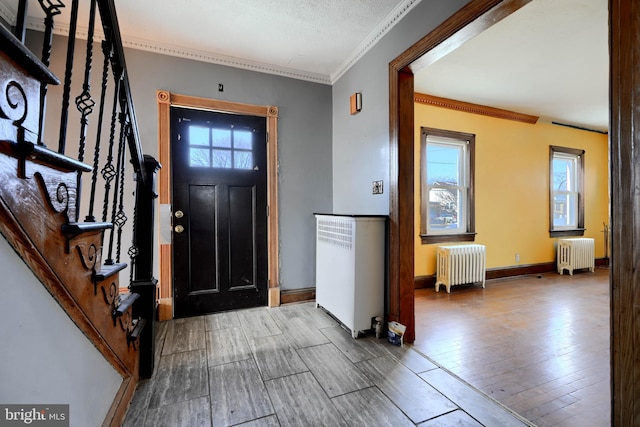 entrance foyer featuring radiator, a healthy amount of sunlight, and wood finished floors