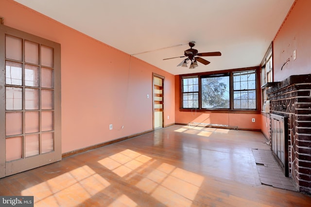 unfurnished living room featuring light wood finished floors, a fireplace, a ceiling fan, and baseboards