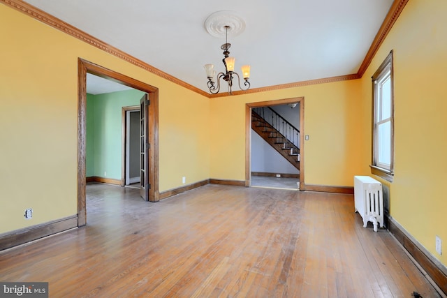 unfurnished room featuring a chandelier, ornamental molding, radiator heating unit, and hardwood / wood-style flooring