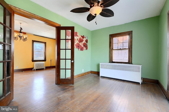 unfurnished room with baseboards, radiator, radiator heating unit, wood-type flooring, and french doors