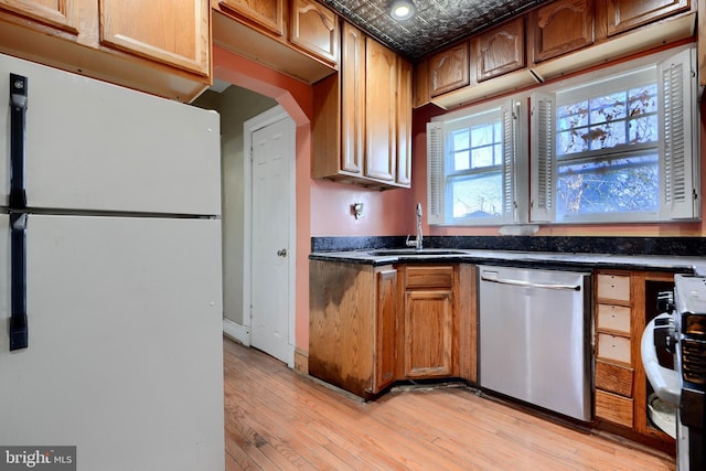 kitchen with an ornate ceiling, dark countertops, stainless steel dishwasher, freestanding refrigerator, and a sink