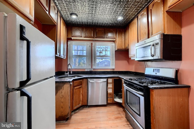 kitchen with stainless steel appliances, a sink, an ornate ceiling, and brown cabinets