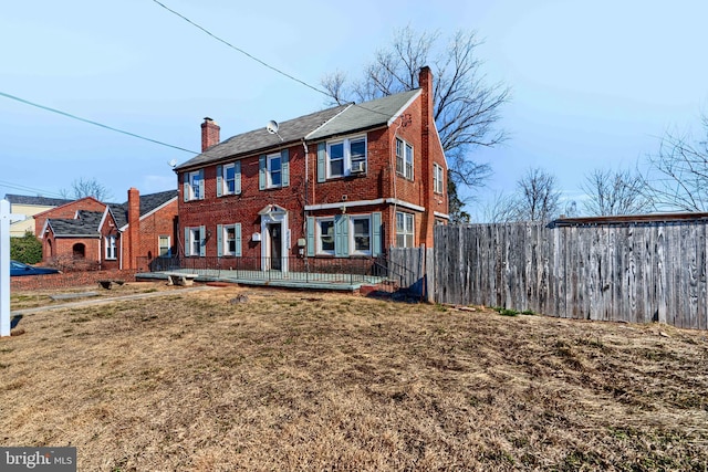 view of front of house with a chimney, a front yard, fence, and brick siding