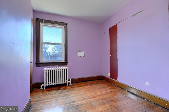 unfurnished room with radiator, baseboards, and hardwood / wood-style floors