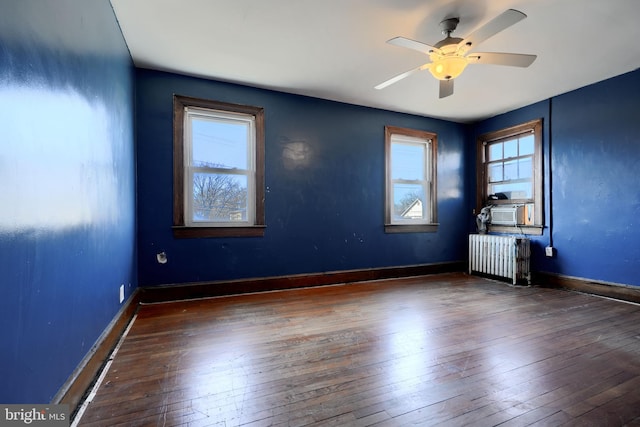 spare room with baseboards, radiator heating unit, ceiling fan, dark wood-type flooring, and cooling unit