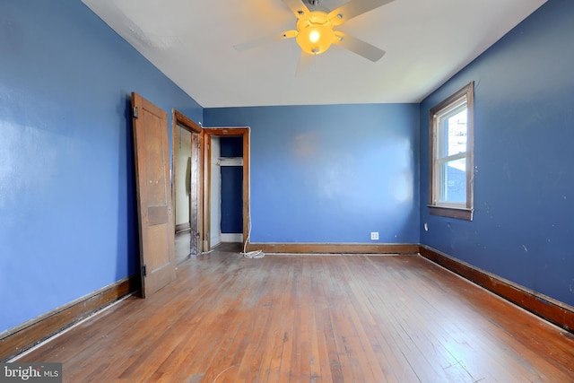 spare room featuring wood-type flooring, ceiling fan, and baseboards