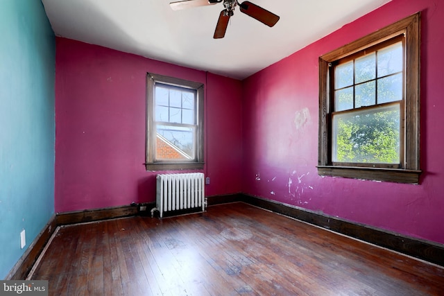 empty room with baseboards, hardwood / wood-style floors, a wealth of natural light, and radiator