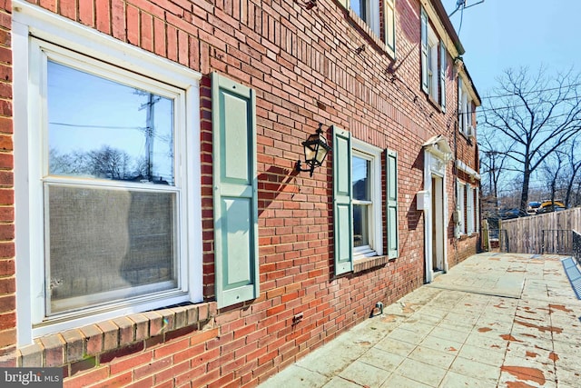 view of home's exterior featuring a patio area, fence, and brick siding