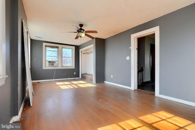 spare room with cooling unit, ceiling fan, baseboards, and wood finished floors