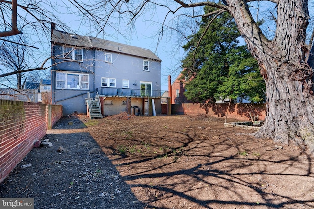 rear view of property featuring fence and stairs