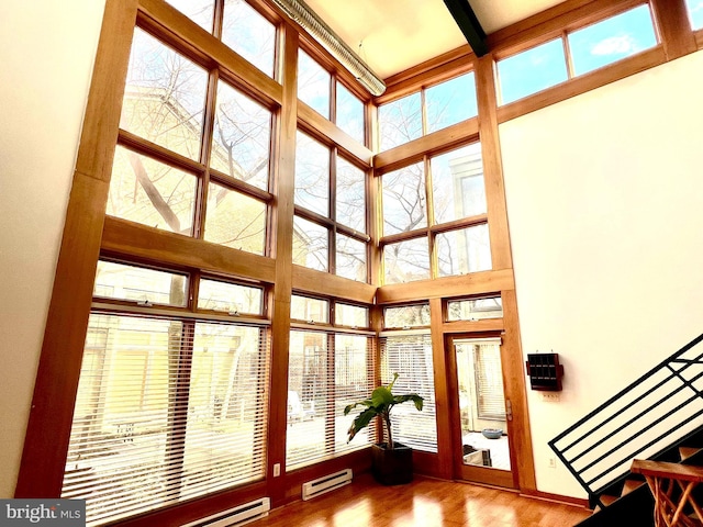 unfurnished sunroom featuring a baseboard heating unit, a baseboard radiator, beam ceiling, and a healthy amount of sunlight