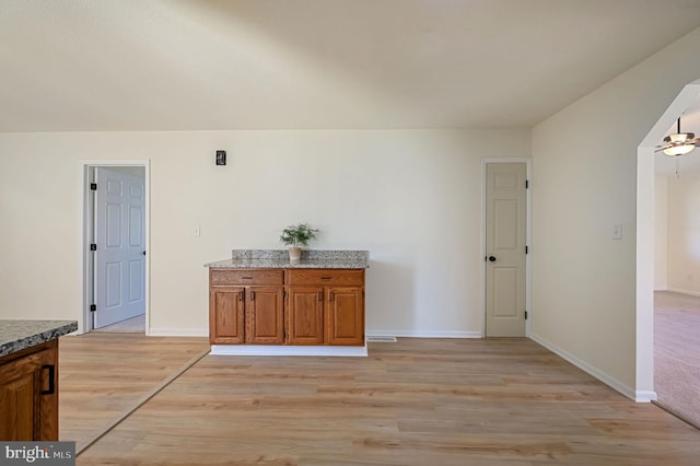 interior space with visible vents, baseboards, arched walkways, light wood-style flooring, and brown cabinets