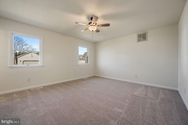 carpeted empty room with a ceiling fan, visible vents, and baseboards