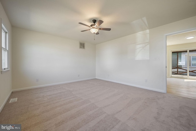 empty room featuring light carpet, baseboards, visible vents, and ceiling fan