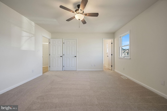 unfurnished bedroom with light carpet, ensuite bath, visible vents, and baseboards