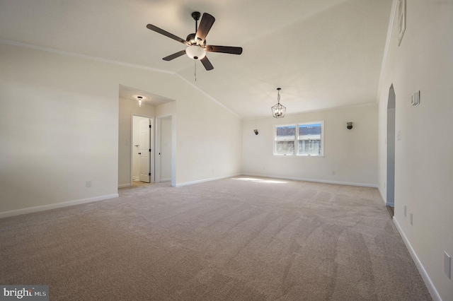 empty room featuring light colored carpet, ornamental molding, vaulted ceiling, baseboards, and ceiling fan with notable chandelier