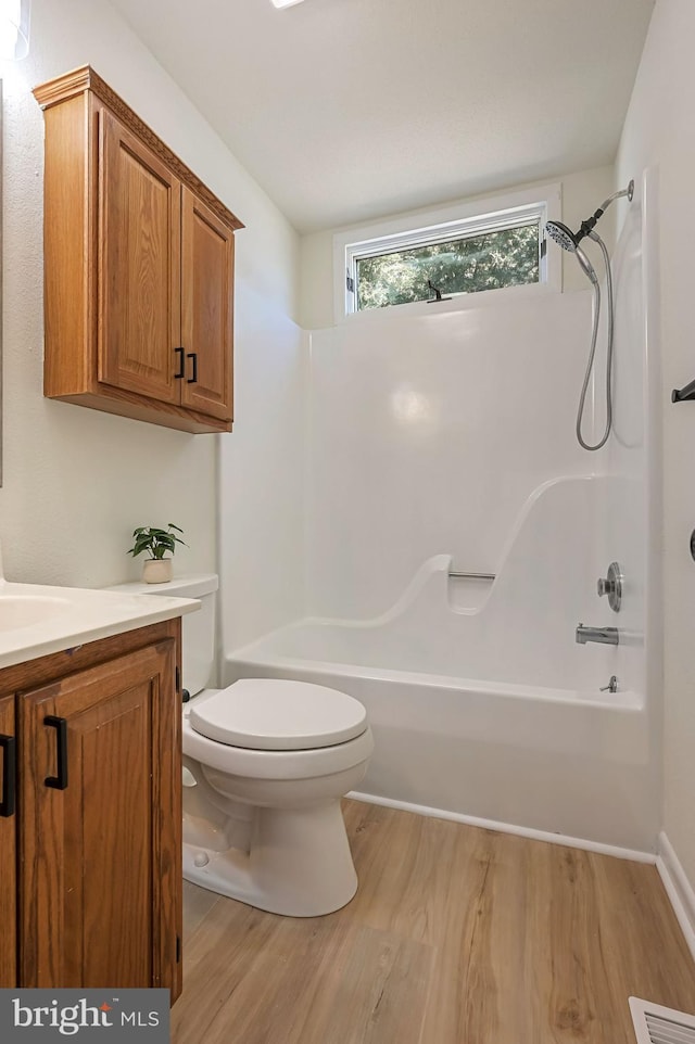 full bath with visible vents, toilet, vanity, wood finished floors, and shower / bathtub combination