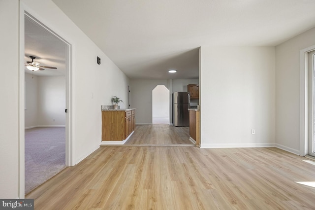 interior space featuring light wood finished floors, a ceiling fan, and baseboards