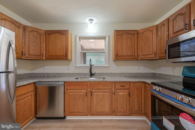 kitchen with stainless steel appliances, brown cabinetry, and a sink