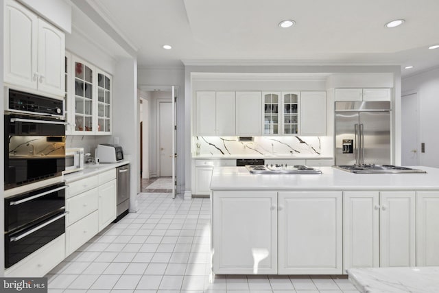 7707 Carlton Pl, Mclean, VA 22102 - kitchen with light countertops, tasteful backsplash, appliances with stainless steel finishes, glass insert cabinets, and white cabinetry