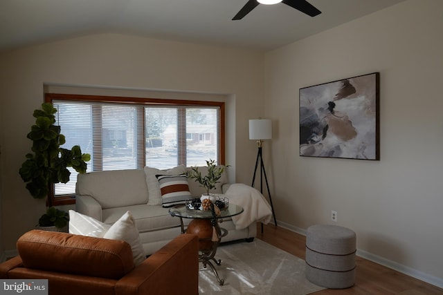 living room with a ceiling fan, baseboards, vaulted ceiling, and wood finished floors