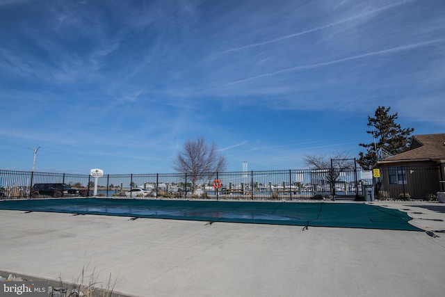 community pool with a patio area and fence