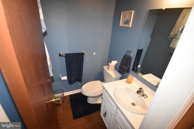 bathroom featuring toilet, baseboards, wood finished floors, and vanity