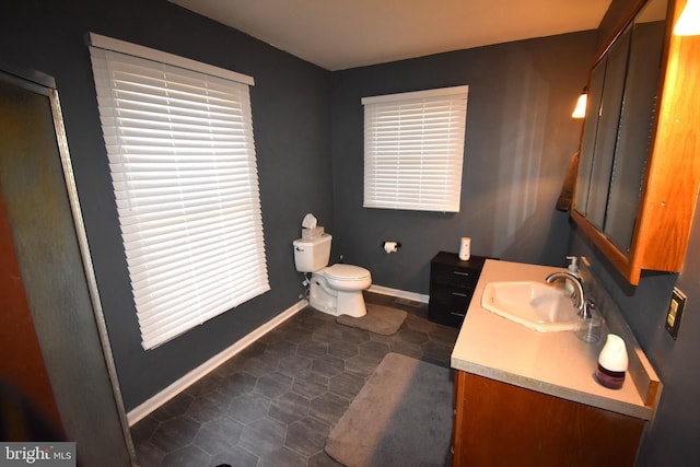 full bathroom featuring toilet, a shower with shower door, baseboards, and vanity