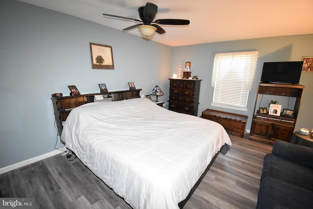 bedroom with a ceiling fan, visible vents, baseboards, and wood finished floors