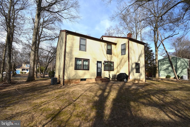 rear view of house with a chimney and cooling unit