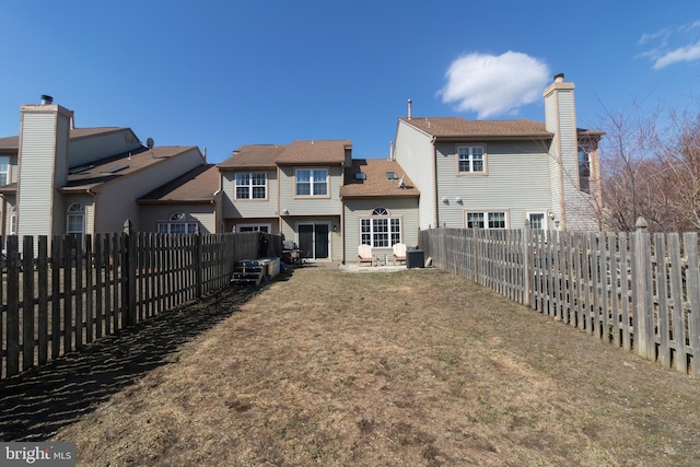 back of house featuring a fenced backyard and a lawn