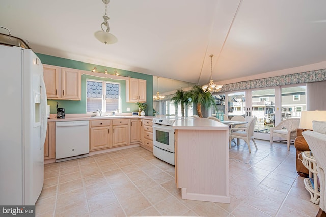 kitchen with a peninsula, white appliances, open floor plan, light countertops, and light brown cabinetry