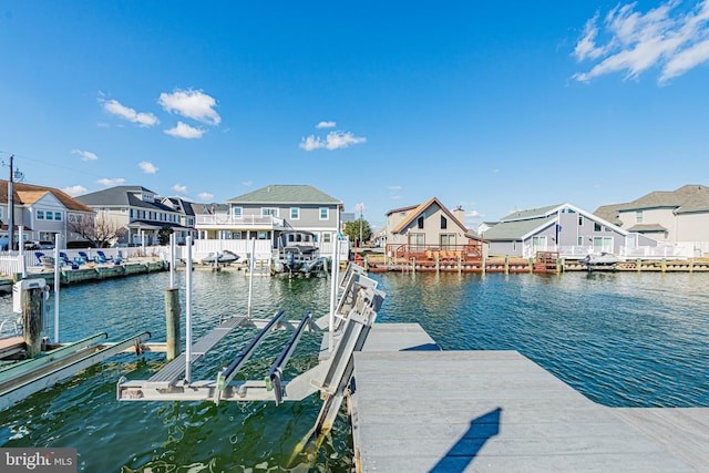 dock area with a water view, boat lift, and a residential view