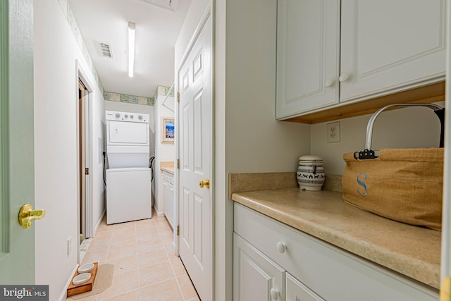 washroom with stacked washer and dryer, cabinet space, visible vents, and light tile patterned floors