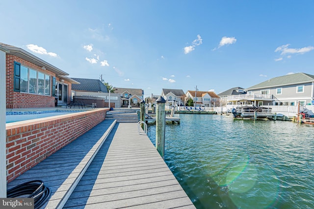 view of dock with a residential view and a water view