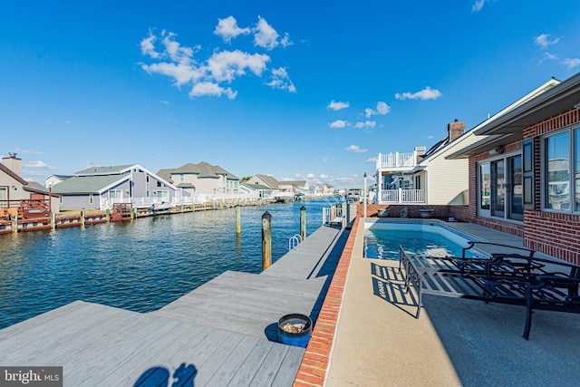 view of dock featuring a water view, a residential view, and a fenced in pool