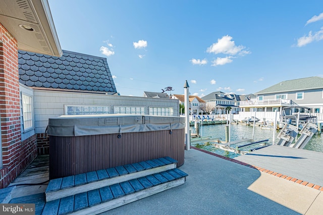 view of patio with a dock, a water view, and a hot tub