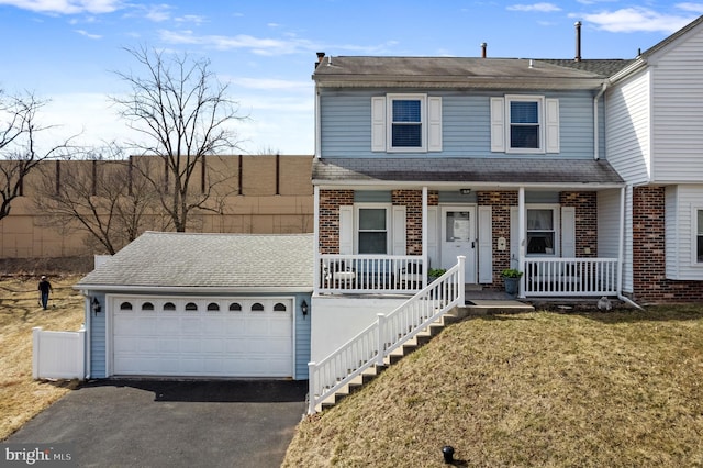 view of front of home with brick siding, roof with shingles, covered porch, driveway, and a front lawn