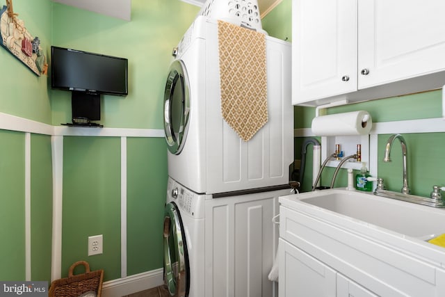 laundry area with a sink, cabinet space, and stacked washer / drying machine