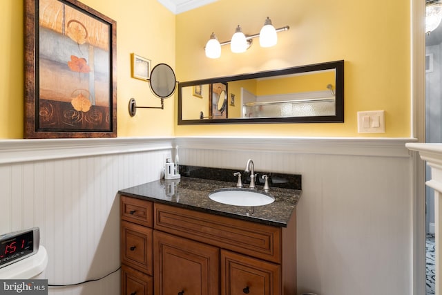 bathroom with toilet, vanity, and wainscoting