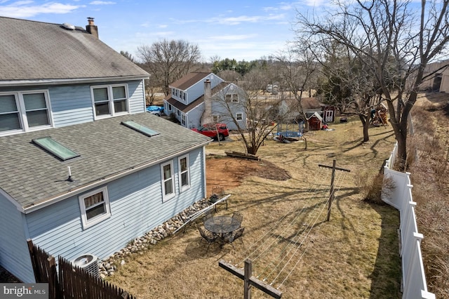 view of home's exterior with a residential view, a chimney, fence, and roof with shingles