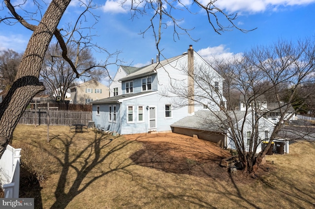 rear view of property with a chimney and fence