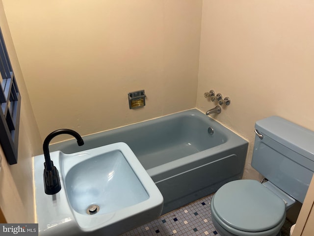 bathroom with a washtub, a sink, toilet, and tile patterned floors